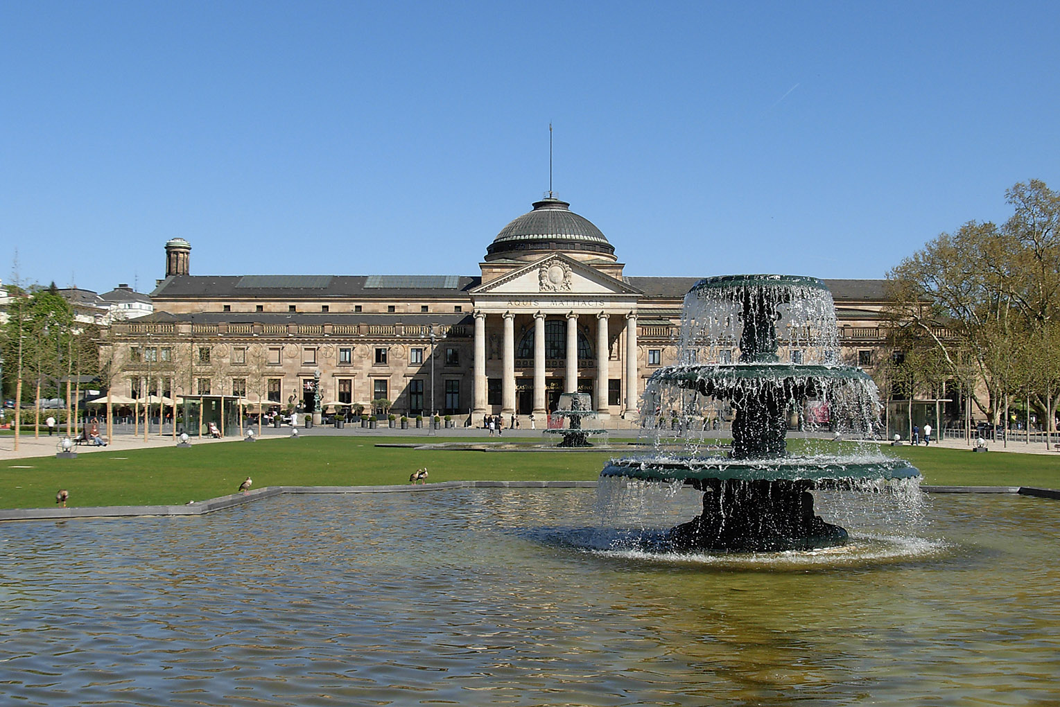 "Bowling Green & Kurhaus Wiesbaden" by Pedelecs by Wikivoyage and Wikipedia. Licensed under CC BY-SA 3.0 via Wikimedia Commons - https://commons.wikimedia.org/wiki/File:Bowling_Green_%26_Kurhaus_Wiesbaden.jpg#/media/File:Bowling_Green_%26_Kurhaus_Wiesbaden.jpg